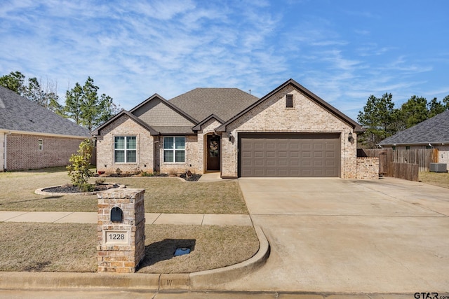 view of front of property with brick siding, an attached garage, fence, roof with shingles, and driveway