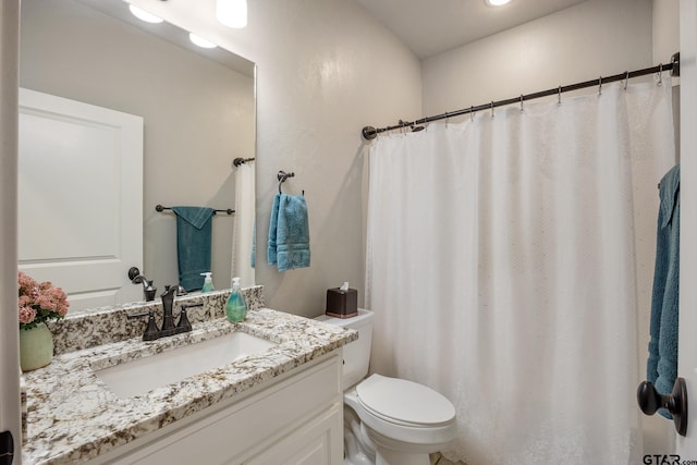 bathroom with curtained shower, toilet, and vanity