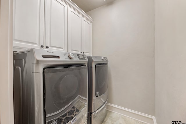 washroom featuring washing machine and dryer, cabinet space, and baseboards