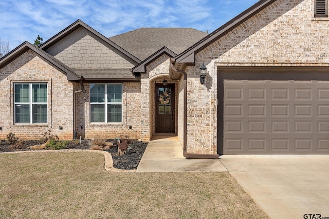 view of front of property featuring an attached garage, a shingled roof, concrete driveway, a front lawn, and brick siding