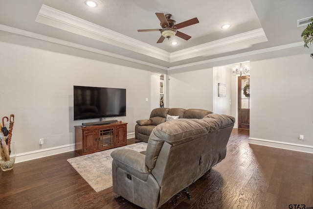 living area with a tray ceiling, ceiling fan with notable chandelier, and dark wood-style flooring