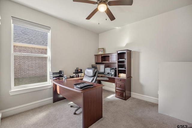 carpeted office space with a ceiling fan and baseboards