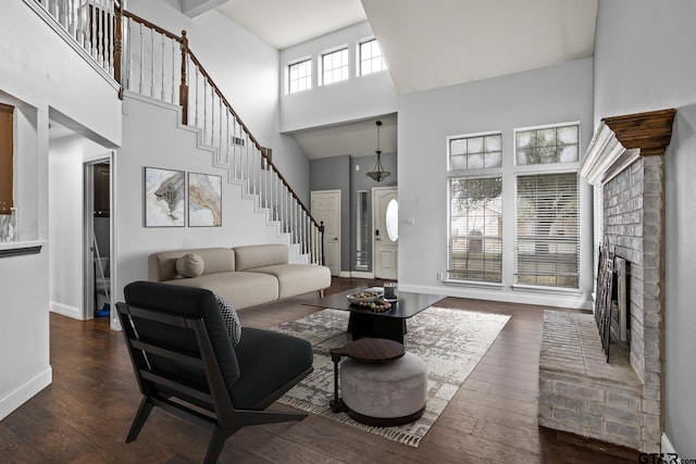501 Morning Glory Cir, Hughes Springs, TX 75656 - living area with a brick fireplace, baseboards, a towering ceiling, dark wood-style floors, and stairs
