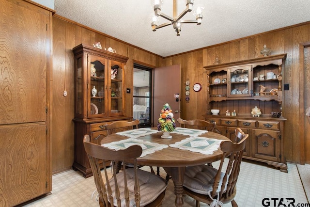 21187 Kristen Dr, Chandler, TX 75758 - dining space with wooden walls, light floors, a chandelier, ornamental molding, and a textured ceiling