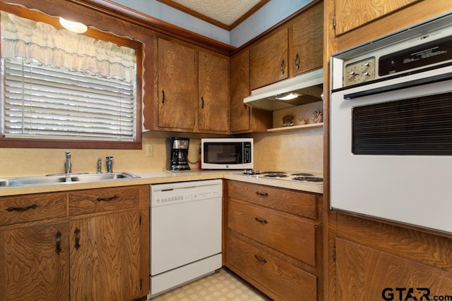 kitchen with white appliances, sink, ornamental molding, and a textured ceiling