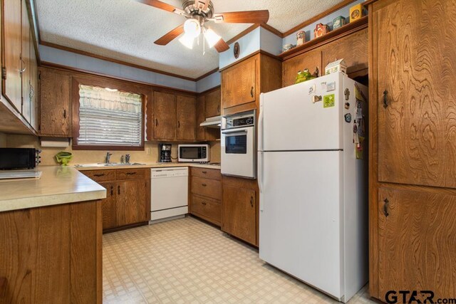 21187 Kristen Dr, Chandler, TX 75758 - kitchen with white appliances, light floors, light countertops, brown cabinetry, and a textured ceiling