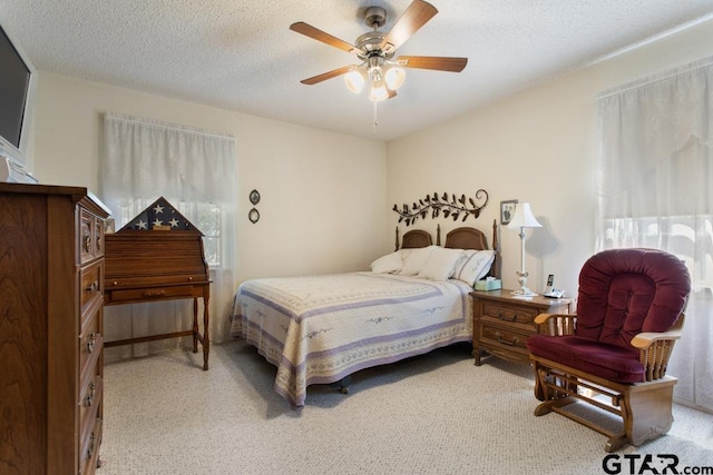 carpeted bedroom with multiple windows, ceiling fan, and a textured ceiling