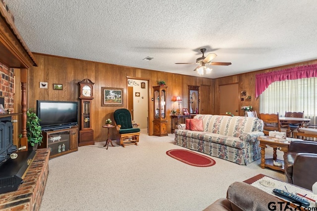 living room featuring wood walls, a textured ceiling, ceiling fan, and carpet floors