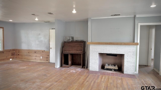 unfurnished living room with wood-type flooring and a brick fireplace