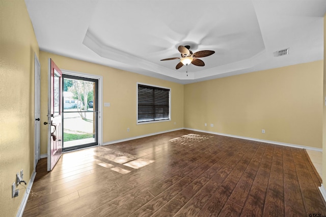 spare room featuring wood-type flooring, a raised ceiling, and ceiling fan