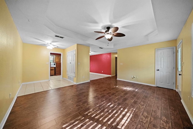 empty room featuring hardwood / wood-style floors, ceiling fan, and a tray ceiling