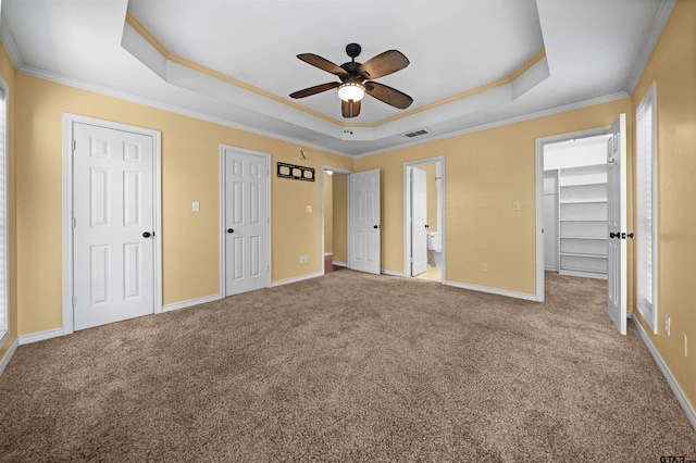 unfurnished bedroom featuring light carpet, connected bathroom, crown molding, and a raised ceiling