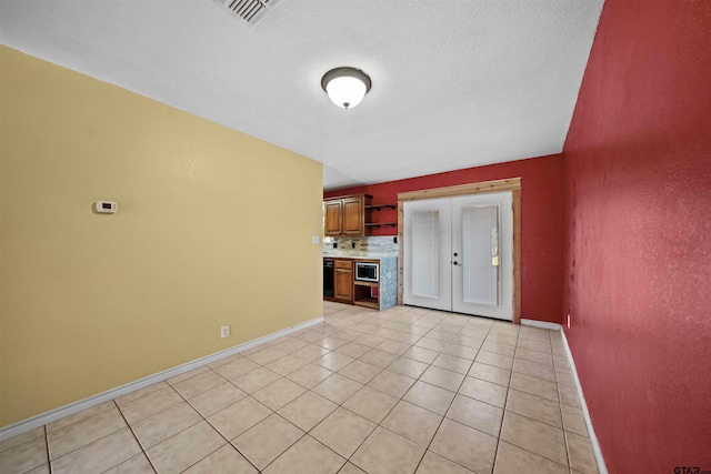 interior space featuring french doors, a textured ceiling, and light tile patterned flooring