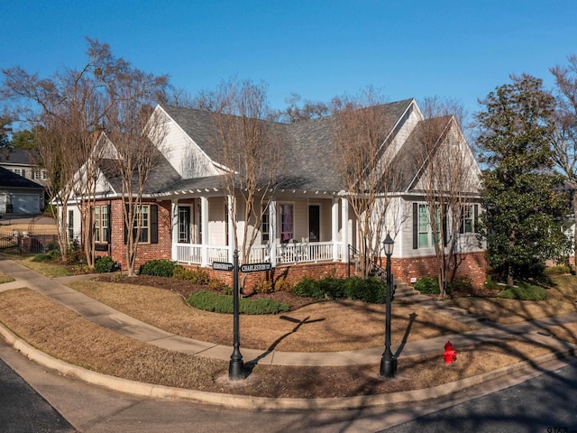 view of front of property with covered porch, roof with shingles, and brick siding