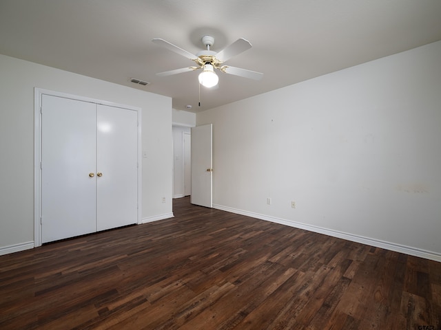 unfurnished bedroom featuring ceiling fan, dark hardwood / wood-style floors, and a closet