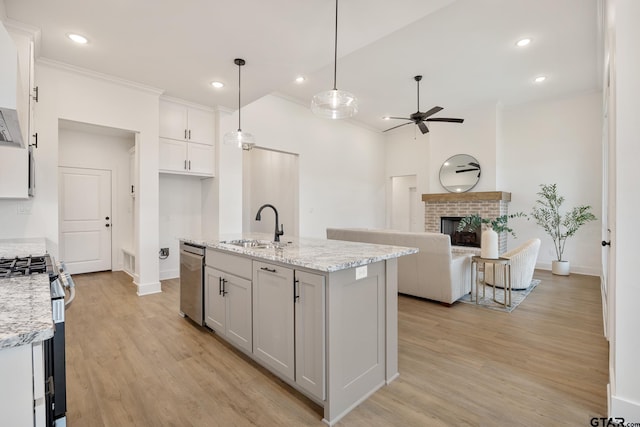 kitchen featuring hanging light fixtures, sink, white cabinetry, light stone counters, and stainless steel appliances