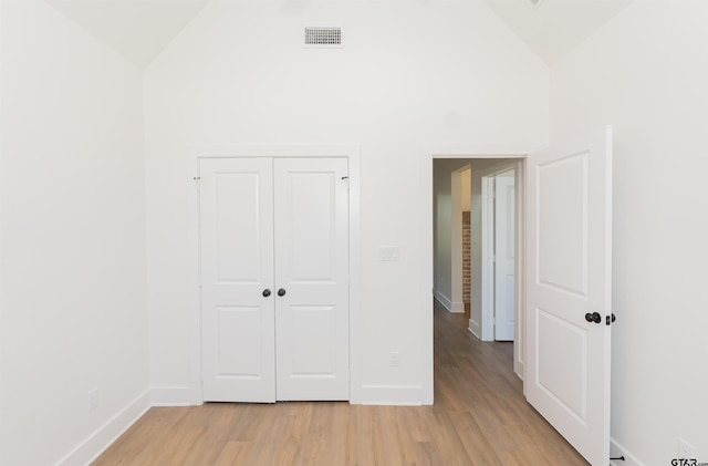 unfurnished bedroom with light hardwood / wood-style flooring, a closet, and vaulted ceiling