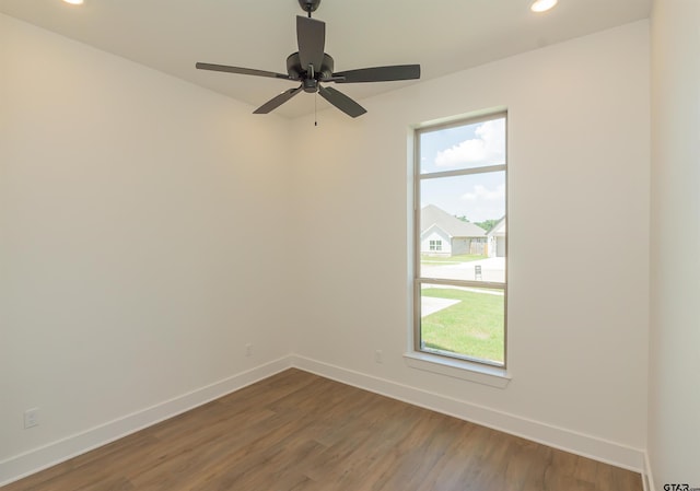 empty room featuring ceiling fan, a wealth of natural light, and dark hardwood / wood-style flooring