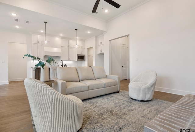 living room featuring ceiling fan, wood-type flooring, and crown molding