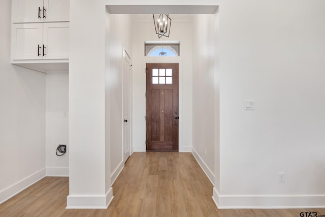 entryway with ornamental molding, light hardwood / wood-style floors, and an inviting chandelier