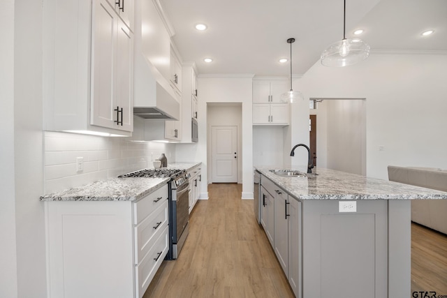 kitchen featuring sink, white cabinets, pendant lighting, a center island with sink, and stainless steel range with gas cooktop