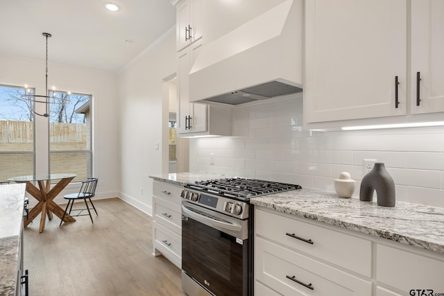 kitchen with white cabinetry, premium range hood, hanging light fixtures, light stone counters, and stainless steel range with gas cooktop