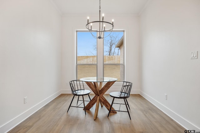 dining room featuring light wood-type flooring, ornamental molding, and an inviting chandelier