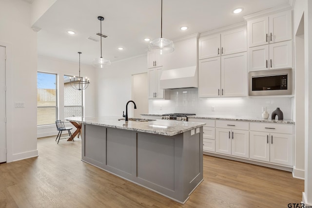 kitchen featuring sink, white cabinets, pendant lighting, and built in microwave