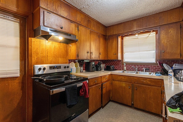 2114 Martin Luther King Blvd, Palestine, TX 75803 - kitchen with electric stove, under cabinet range hood, a sink, brown cabinets, and wooden walls