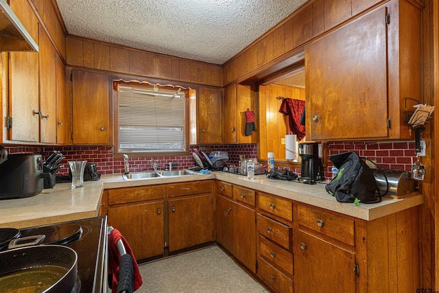 2114 Martin Luther King Blvd, Palestine, TX 75803 - kitchen with range with electric cooktop, a sink, light countertops, brown cabinetry, and a textured ceiling