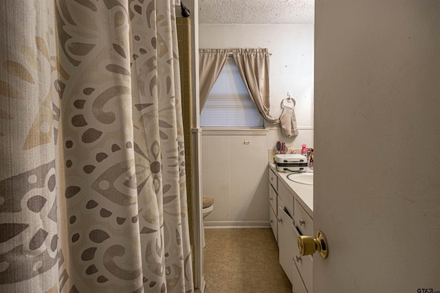 2114 Martin Luther King Blvd, Palestine, TX 75803 - bathroom with double vanity, a textured ceiling, tile patterned flooring, toilet, and curtained shower