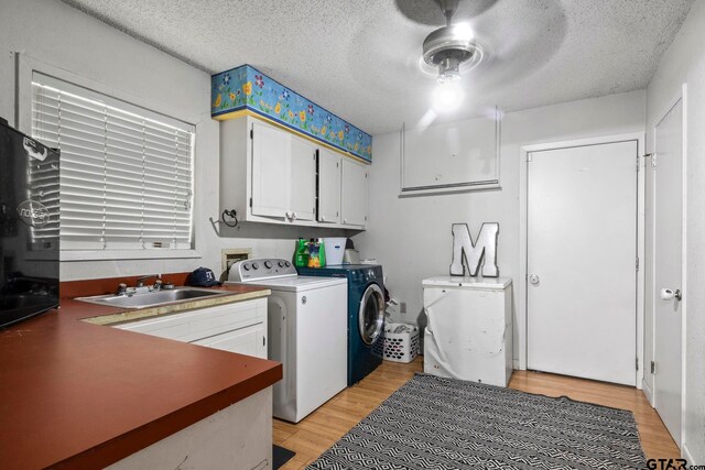 laundry room featuring cabinets, sink, washing machine and clothes dryer, light hardwood / wood-style floors, and ceiling fan