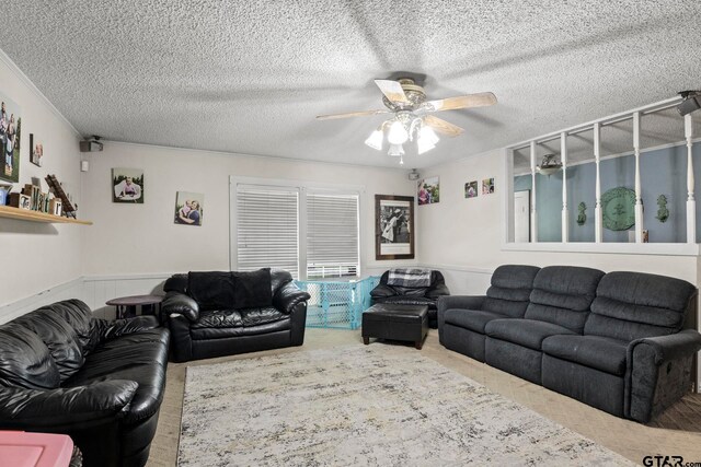 living room with a textured ceiling, ceiling fan, and wainscoting