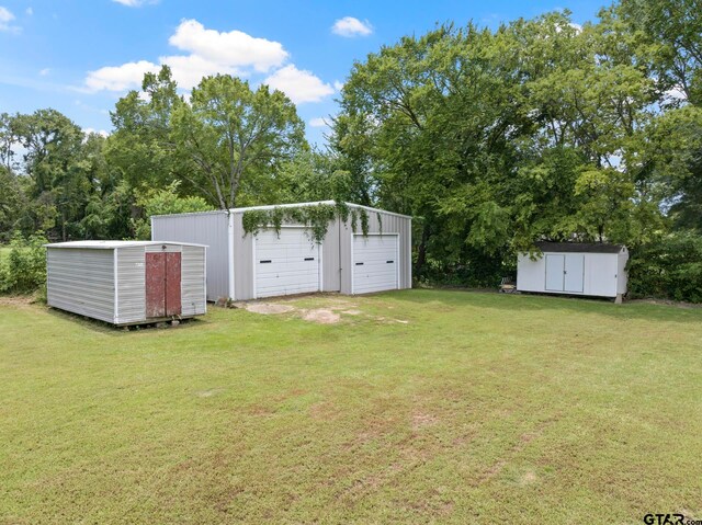 view of yard featuring central air condition unit, an outdoor structure, a detached garage, and a storage shed