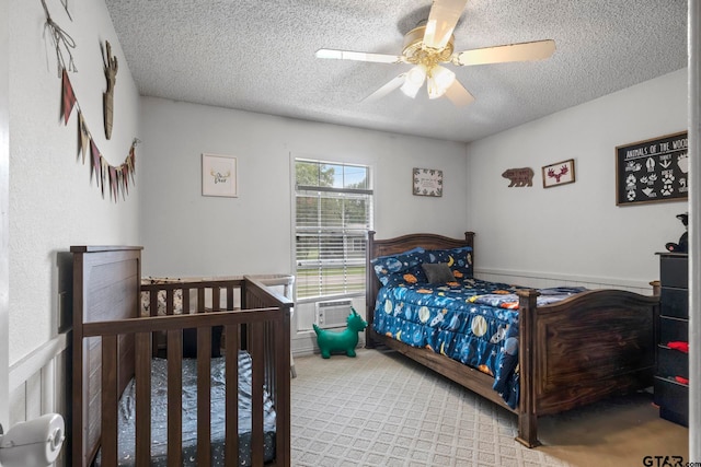 bedroom featuring carpet floors, a wall mounted air conditioner, ceiling fan, and a textured ceiling