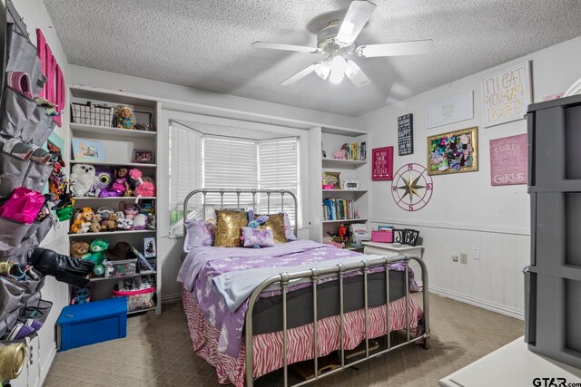 carpeted bedroom with a textured ceiling, wood walls, and ceiling fan