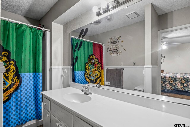 bathroom with vanity, ceiling fan, a textured ceiling, and toilet