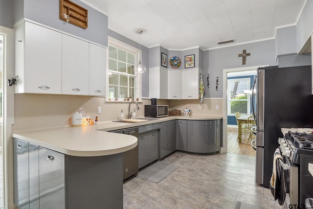 kitchen with appliances with stainless steel finishes, a sink, gray cabinets, a peninsula, and visible vents