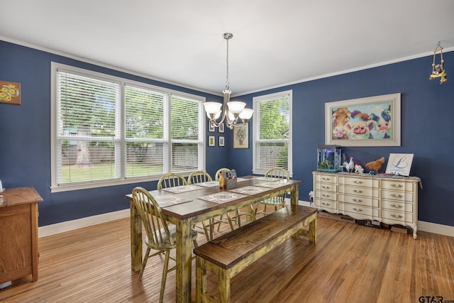 dining space featuring baseboards, ornamental molding, light wood finished floors, and a chandelier