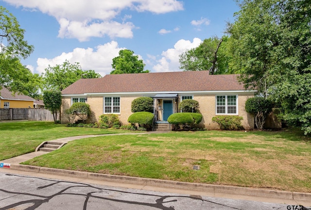 ranch-style home with fence, brick siding, and a front yard