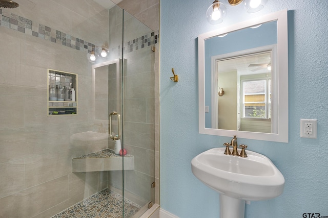 bathroom with a sink, a textured wall, and a shower stall