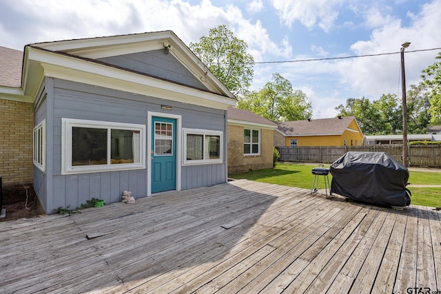 wooden terrace with area for grilling, a lawn, and a fenced backyard