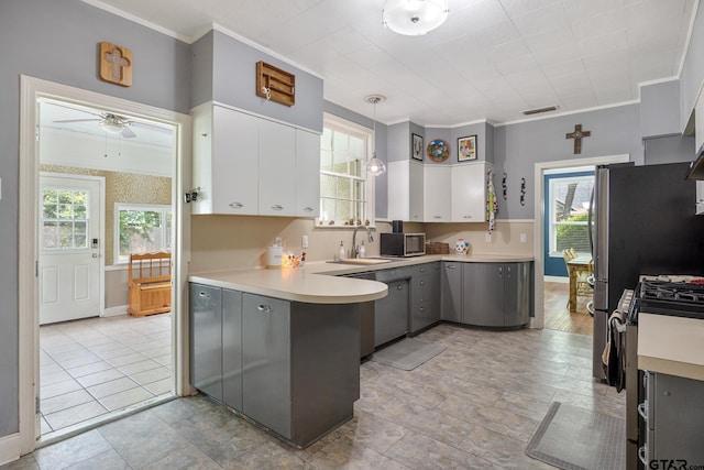 kitchen with crown molding, appliances with stainless steel finishes, a sink, a peninsula, and gray cabinetry