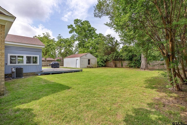 view of yard with a storage shed, a deck, central AC unit, an outdoor structure, and a fenced backyard