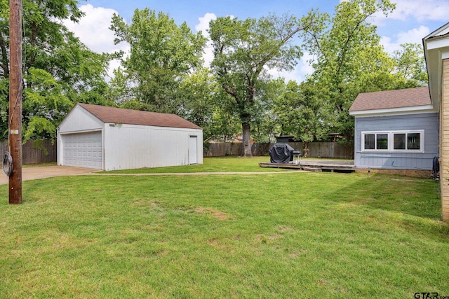 view of yard featuring fence, a detached garage, an outbuilding, and a wooden deck