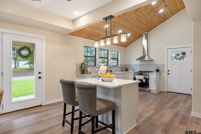 702 W Paschal St, Troup, TX 75789 - kitchen featuring stainless steel electric range, wall chimney range hood, light countertops, decorative backsplash, and a breakfast bar
