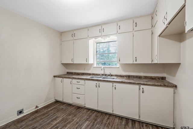 kitchen with a sink, baseboards, dark wood-type flooring, dark countertops, and white cabinets