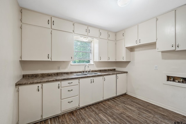 kitchen featuring a sink, dark countertops, baseboards, and dark wood-type flooring