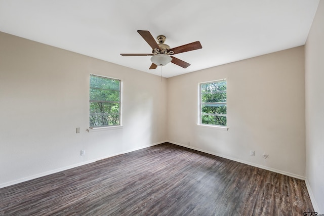 empty room featuring dark wood finished floors, a ceiling fan, and baseboards