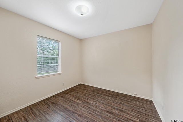 spare room with dark wood finished floors and baseboards
